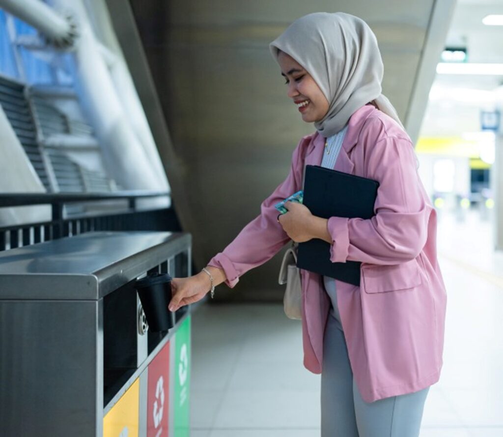 Business woman throwing garbage in trashcan in an Industrial area