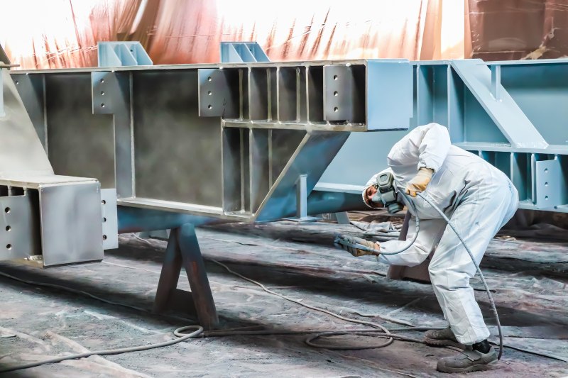 Industrial worker applying protective coating during facility painting project