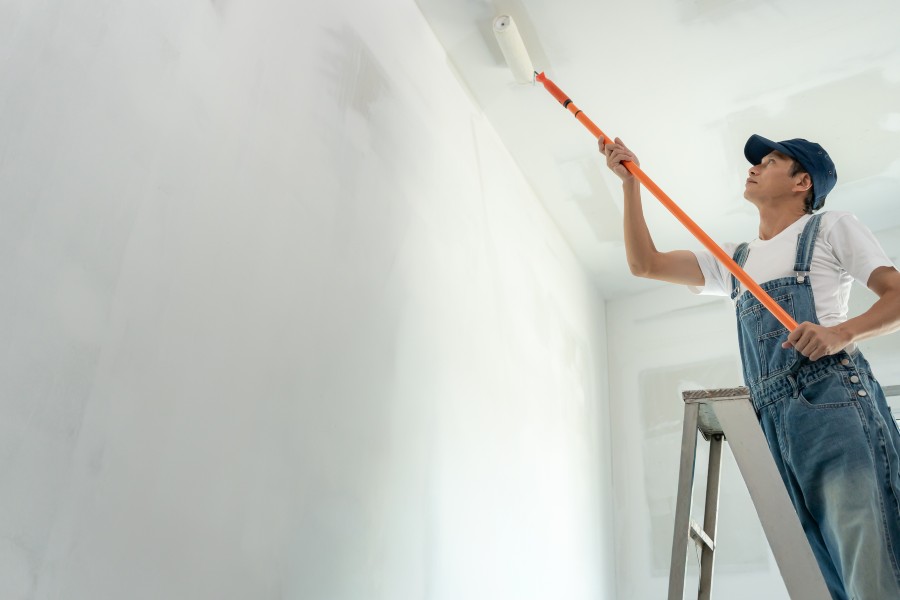 Industrial painting contractor applying protective coating to facility walls during maintenance project