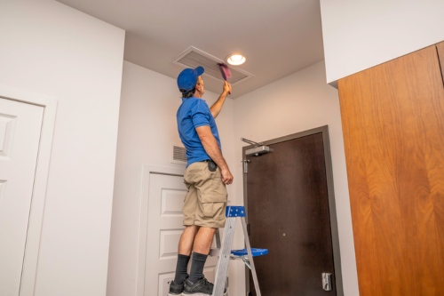 Professional cleaning an HVAC air duct vent as part of routine air duct cleaning
