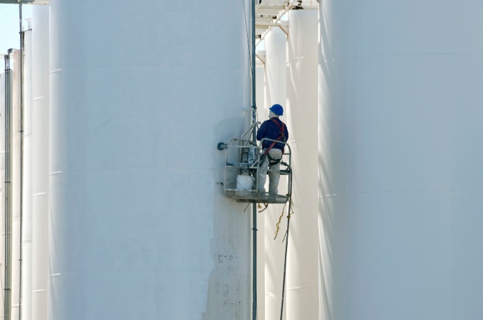 Industrial technician performing cleaning and maintenance on storage silos